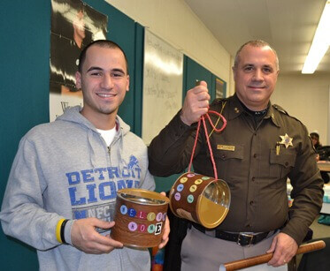 Macomb County Sheriff Anthony Wickersham and one of his mentor team members show off the bird feeders they made for their community service project.